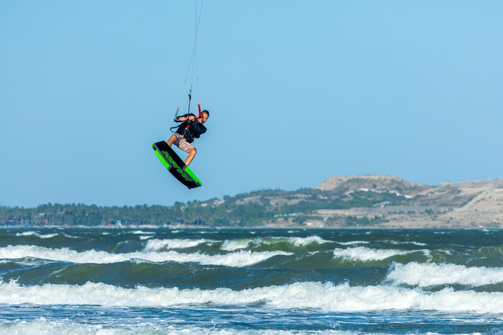 A kitesurfer high in the air above the waves